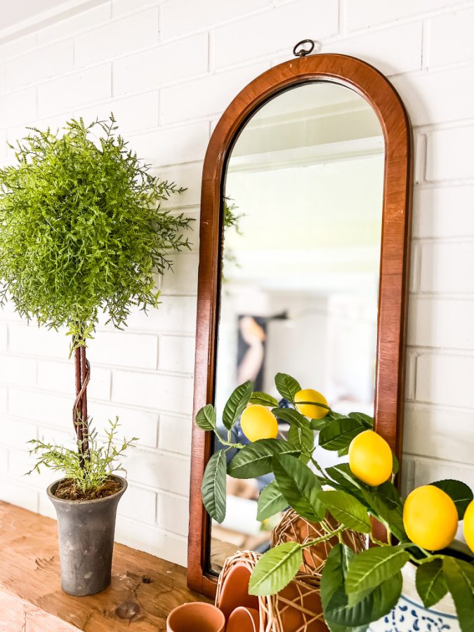 A simple summer mantel with lemons, mirrors and topiaries.