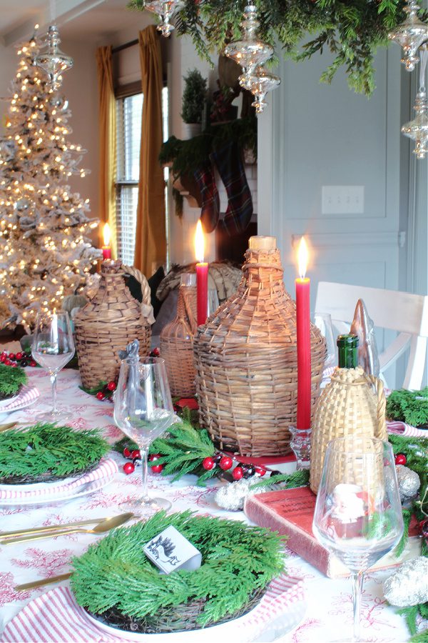 Wicker demi johns, candles, greenery and Christmas lights make this table ready for Christmas dinner!
