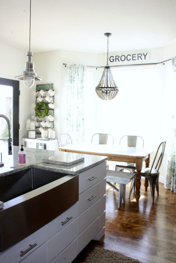 A kitchen with a white island, wood floors, white walls and black interior doors with white trim.