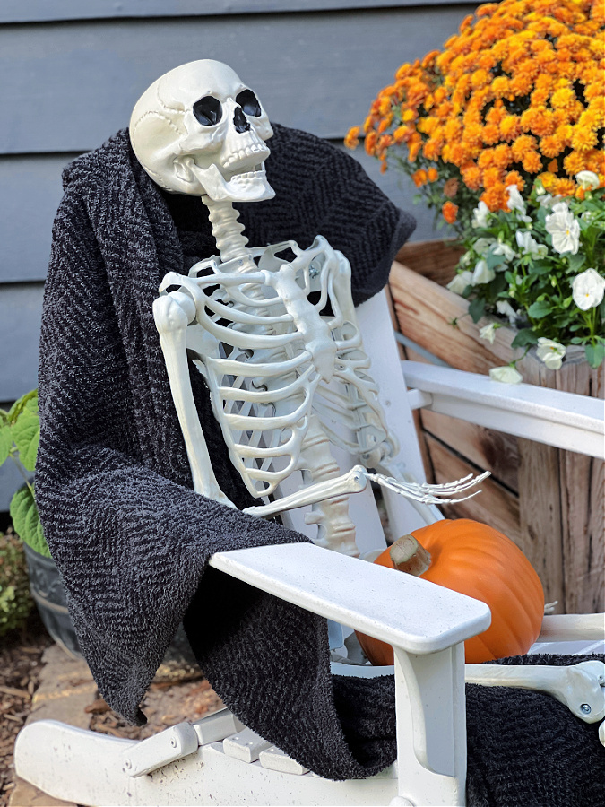 Skeleton sitting in Adirondack chair with black blanket