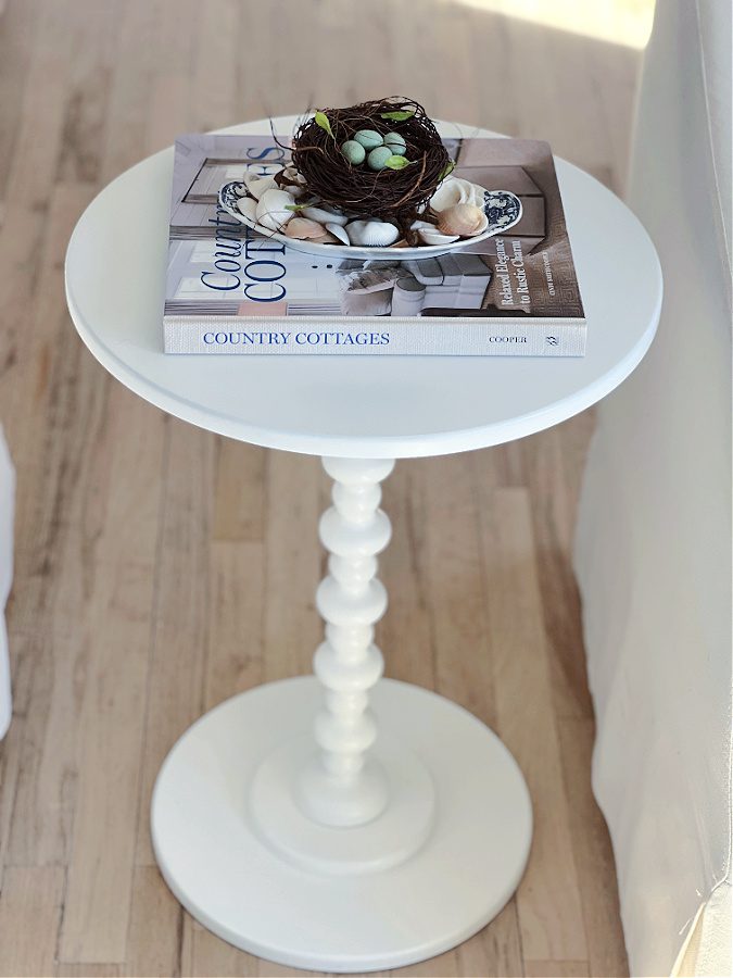 Spindle table with book, plate of shells and nest on top.