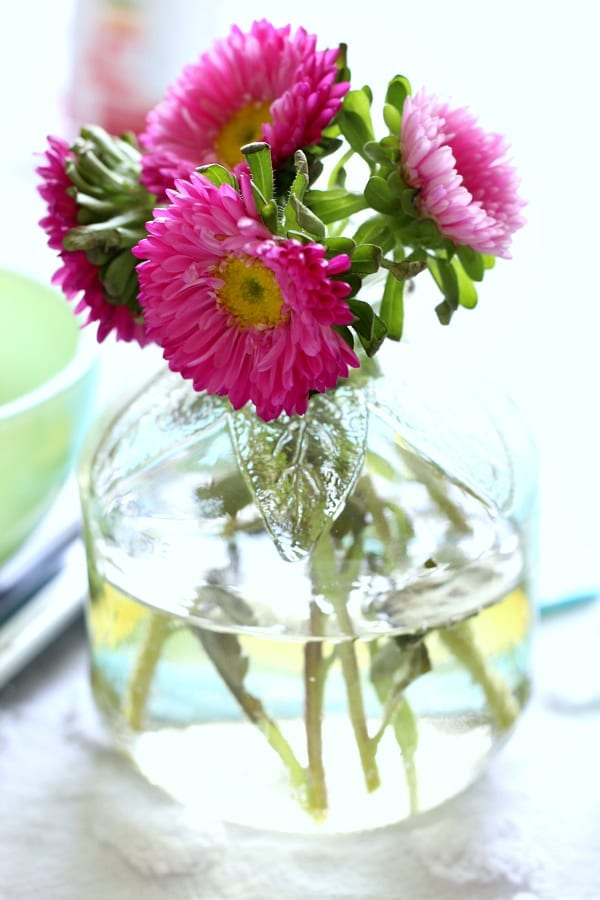 Idea: Bargain flowers and recycled glass juice bottles make the perfect vases for a tea party.