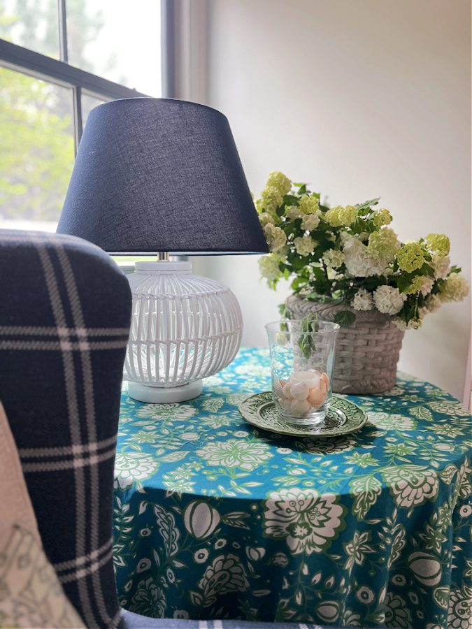 Blue and green Floral covered table with lamp, candle and floral arrangement. 