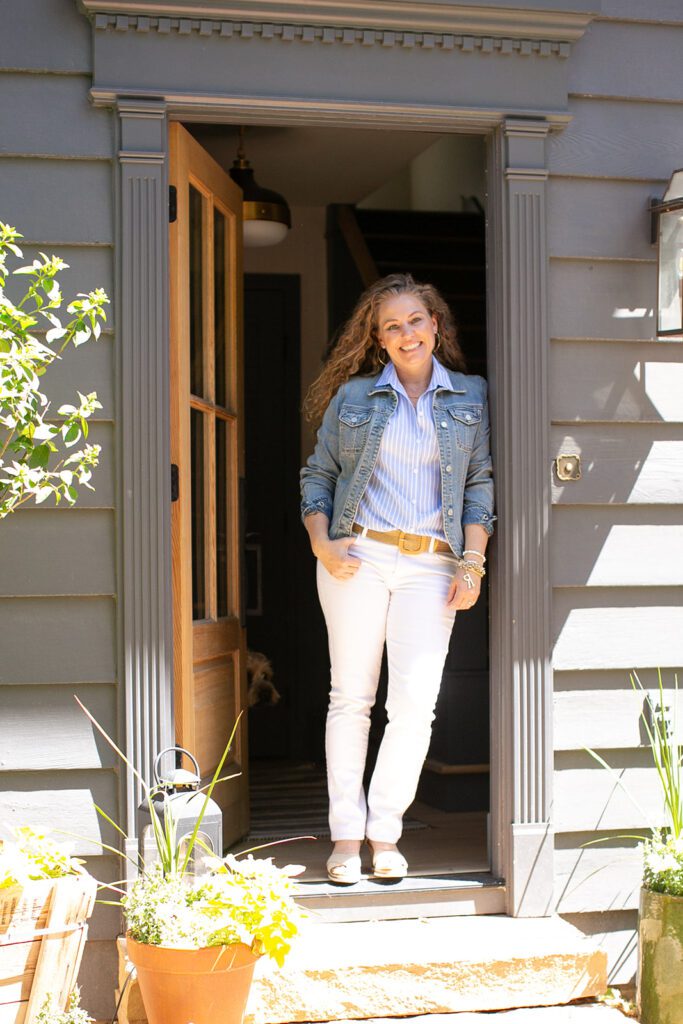 A woman stands in a doorway with a yellow front door and black exterior paint