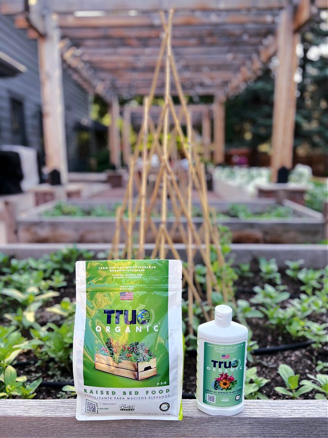 Fertilizer for cut flowers from TRU Organic. Liquid form and solid, setting in front of zinnias just starting to grow.