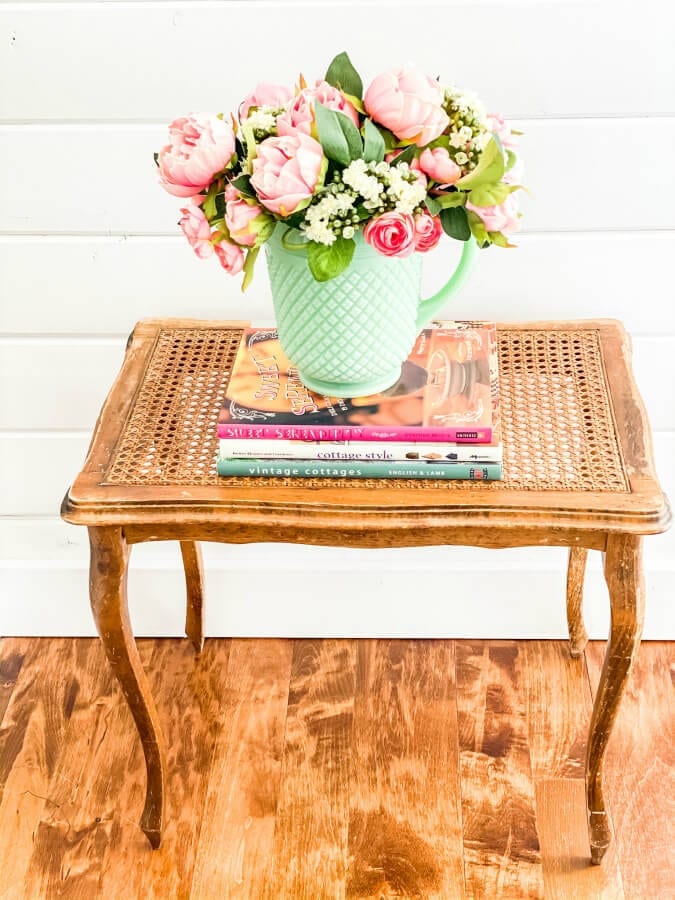 A faux flower arrangment with pink and white flowers in a jadeite pitcher.