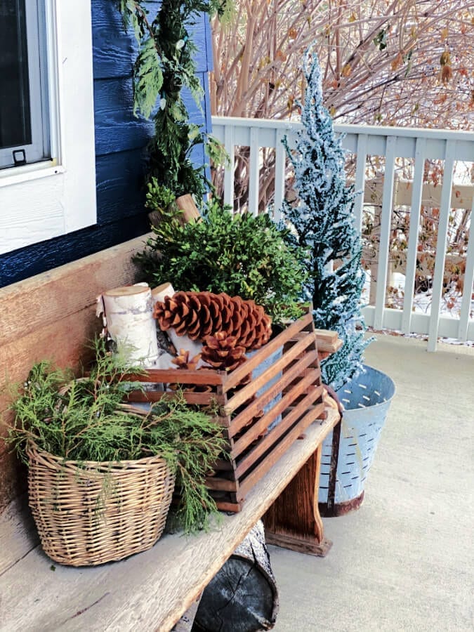 Winter porch decor: pine cones, greens, birch logs and vintage decor